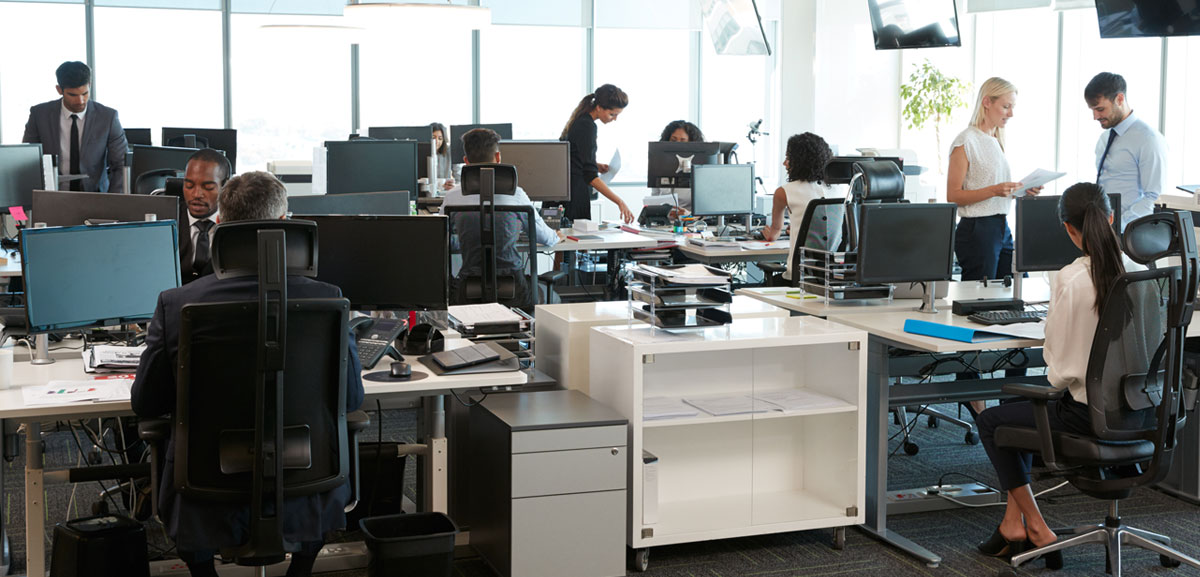 Interior of a busy open plan office with technology staff and computers, printers, monitors and phones