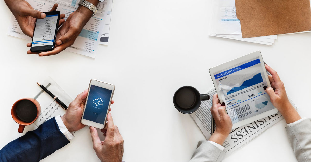 hands holding mobile devices over conference table