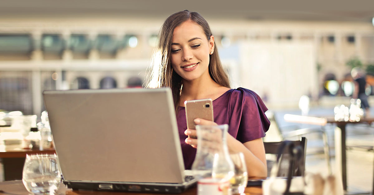 Young woman using two-factor authentication on her laptop and phone